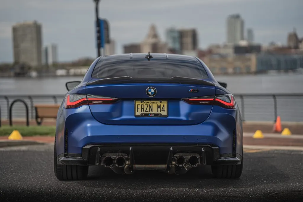 Blue BMW G82 M4 Competition from behind with a carbon trunk spoiler and a finned carbon rear diffuser