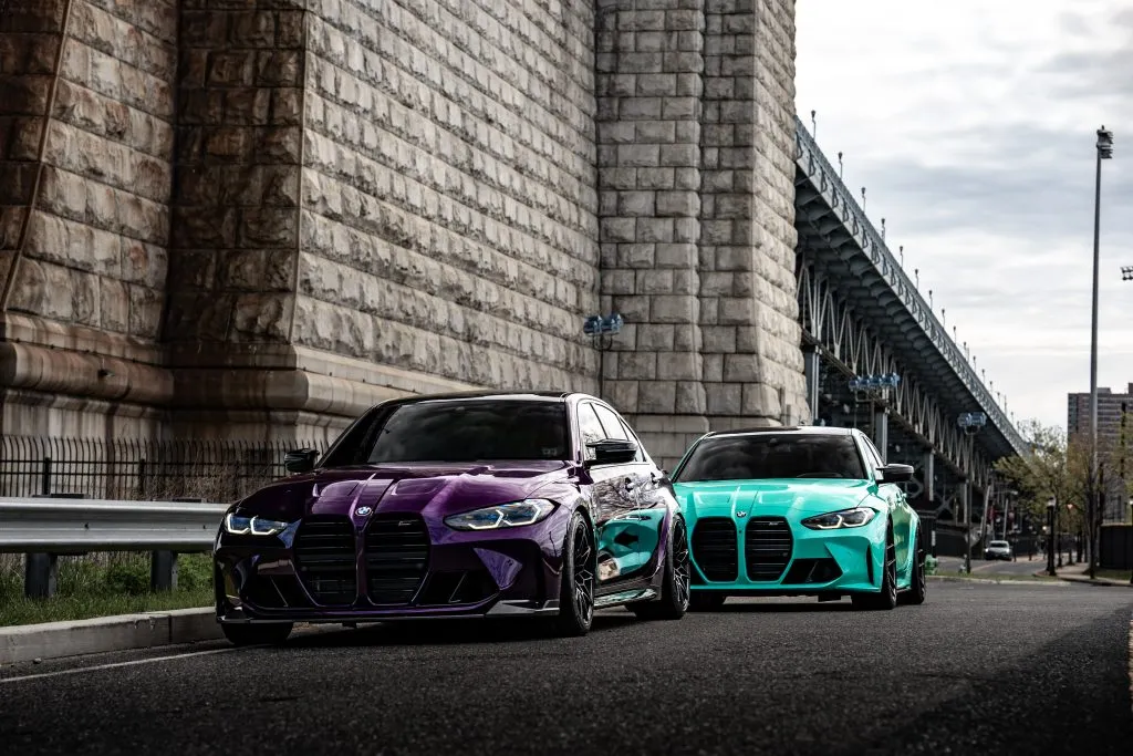 Purple and teal G80 M3s by the bridge wall
