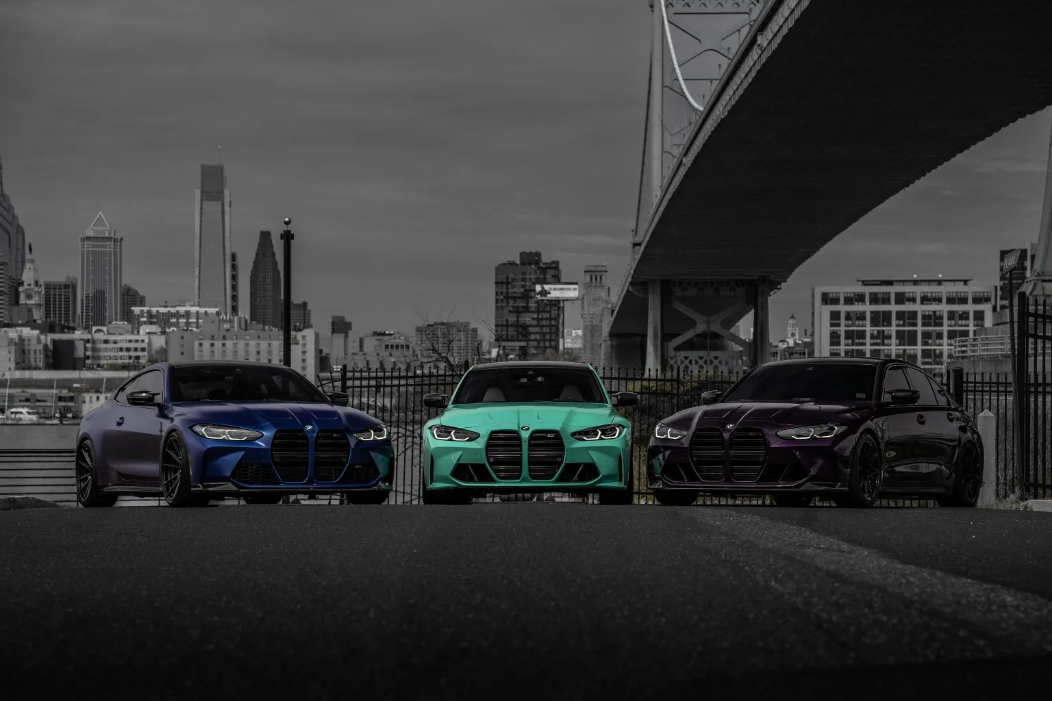 Blue BMW G82 M4 with teal and purple G80 M3s and the Philadelphia skyline