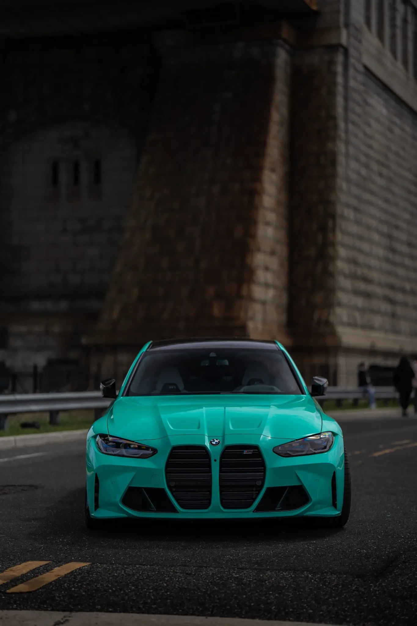 Teal BMW M3 in front of the stone tower of the Ben Franklin Bridge