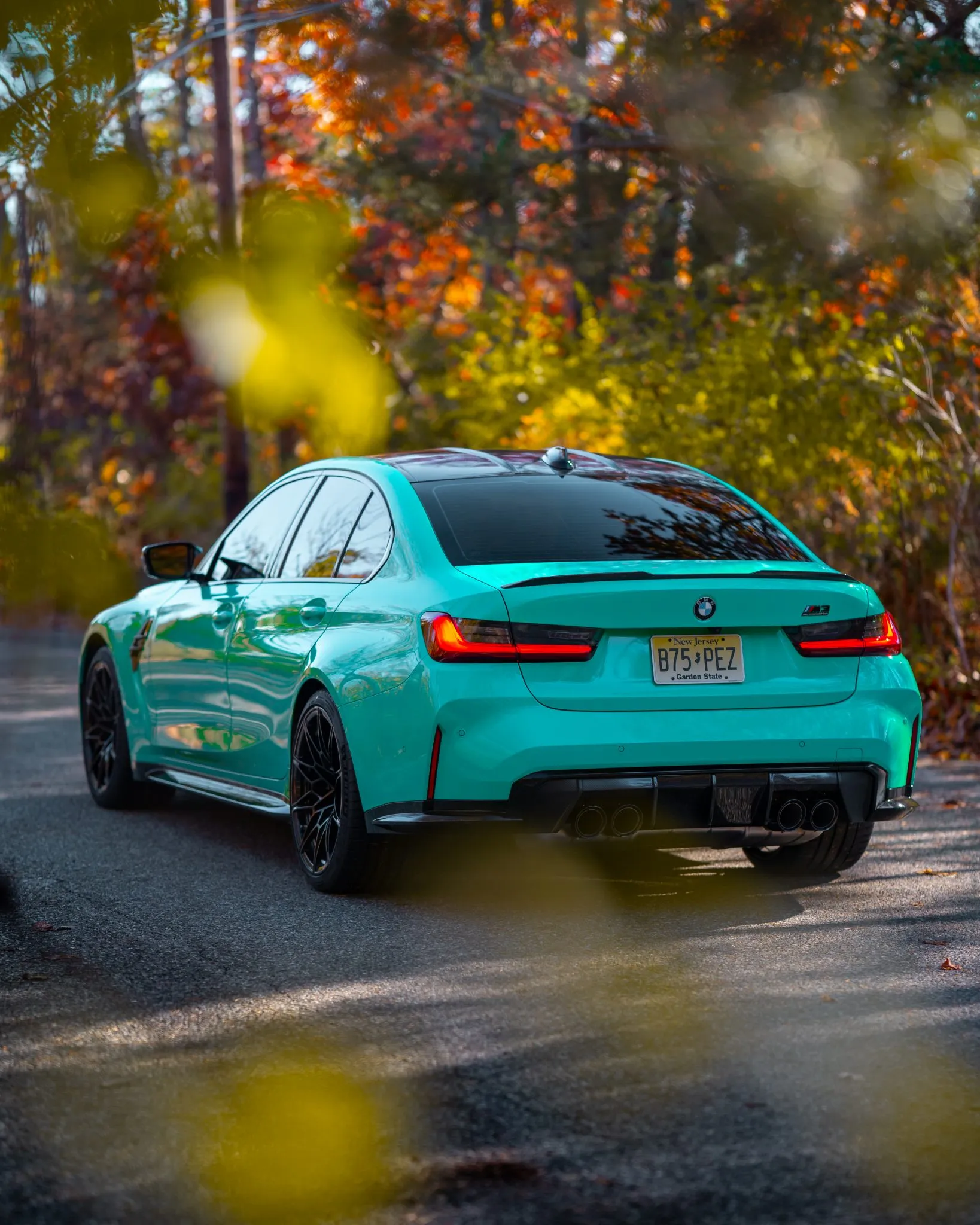 Teal BMW G80 M3 among autumn leaves