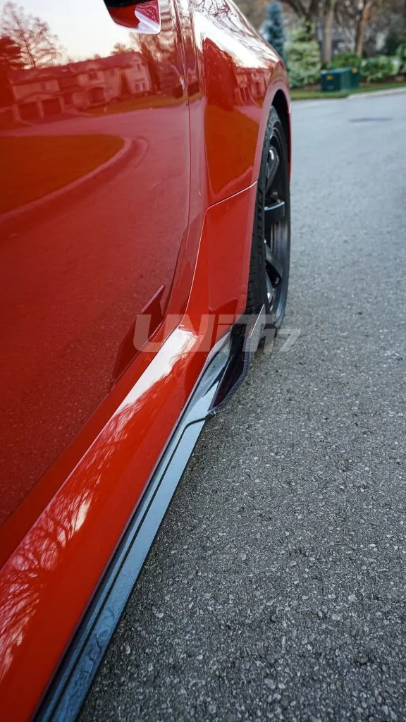 Red BMW M2 side sill with a carbon fiber side skirt ending in a raised winglet by the wheel