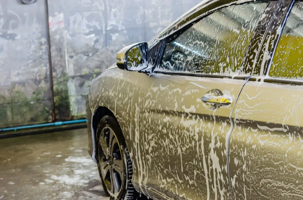 A car covered in soap foam inside a car wash bay